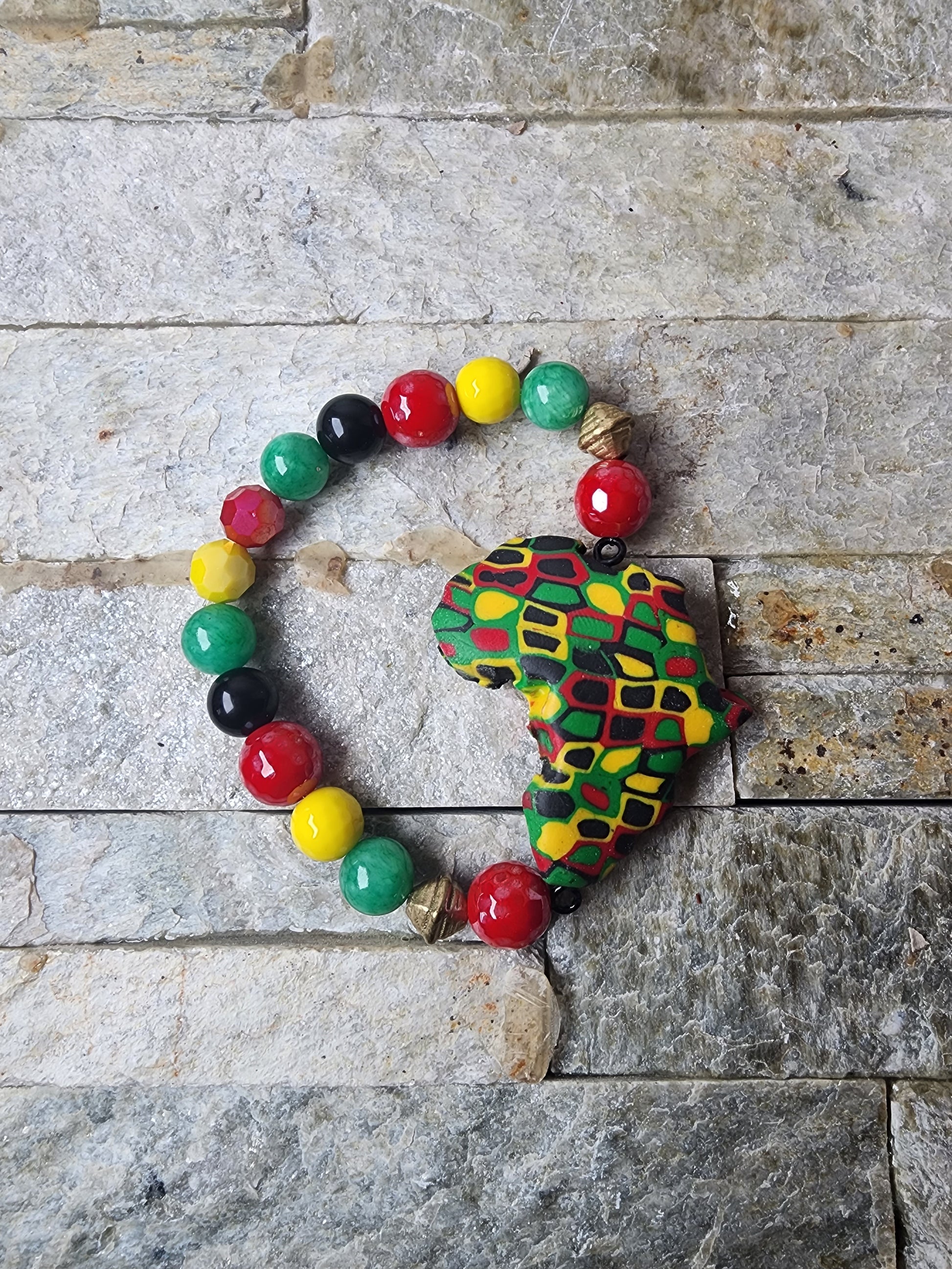 Handmade bracelet with polymer clay beads in Pan-African colors,  jade gemstones, and a bold Africa-shaped focal bead — honoring heritage and spiritual power.