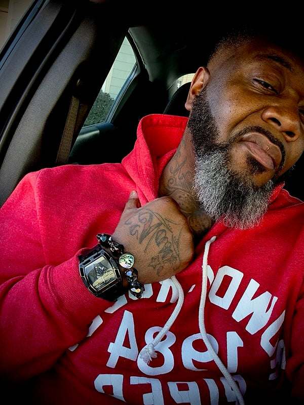 Close-up of a Black man’s wrist wearing a black gemstone bracelet stacked with a bold luxury watch — powerful statement accessory for men.