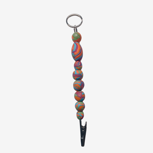 Colorful polymer clay card clips with bold patterns, spikes, roses, feathers, and sculpted designs — wearable mini artworks that fuse art, originality, and utility