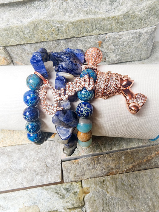 KISHA THE PROTOTYPE BRACELET STACK WITH ROYAL BLUES AND ROSE GOLD CHARMWORK - BOLD, HEALING-CENTERED AND CREATIVITY LAYERED.