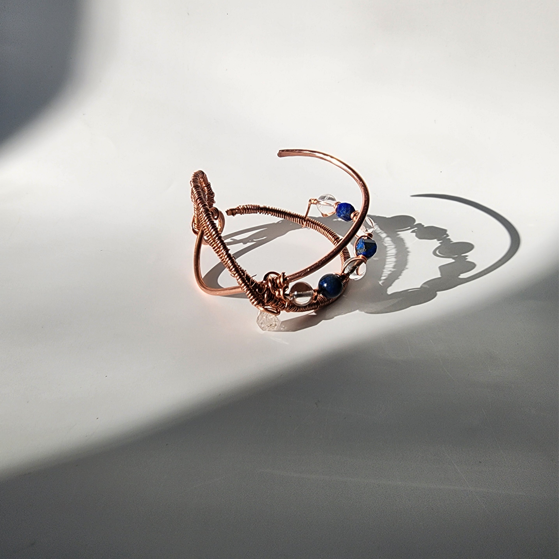 ASE copper crystal cuff bracelet with dramatic shadow highlighting lapis lazuli clear quartz and copper wire wrap